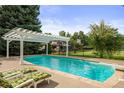 Relaxing backyard oasis with a pool, diving board, lounge chairs, and a pergola; the perfect space for summer fun at 6211 E Orchard Dr, Greenwood Village, CO 80111