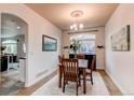 Cozy dining room with wood table set under a chandelier, framed by an arched doorway and a large bright window at 6647 Lynx Cv, Lone Tree, CO 80124