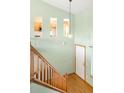 Foyer with hardwood floors, staircase with wooden railing, high ceilings, and glimpses of the kitchen at 8879 Apache Plume Dr, Parker, CO 80134