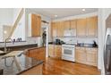 Kitchen features warm wood cabinetry, granite countertops, white appliances, and hardwood floors at 16665 Kenuil St, Brighton, CO 80603
