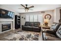 Cozy living room featuring a fireplace, plush seating, and a ceiling fan for comfort at 4997 Collinsville Pl, Highlands Ranch, CO 80130