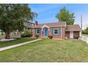 Charming brick home with bright blue door and shutters with grassy front lawn at 1691 Roslyn St, Denver, CO 80220