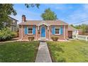 Charming brick home with bright blue door and shutters with grassy front lawn at 1691 Roslyn St, Denver, CO 80220