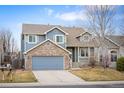 Charming two-story home featuring blue siding, brick accents, a covered porch, and a well-manicured front yard at 13313 Elizabeth St, Thornton, CO 80241