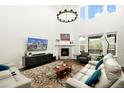 Bright living room with high ceilings, fireplace, and large windows showcasing the outdoor view at 7167 Hyland Hills St, Castle Pines, CO 80108