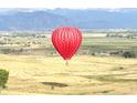 Vibrant red hot air balloon floats over scenic landscape with mountain views at 227 Powderhorn Trl, Broomfield, CO 80020