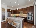 Open kitchen featuring stainless steel appliances, dark wood cabinets, and a large island with seating at 10258 W Coal Mine Pl, Littleton, CO 80127