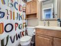 Cozy bathroom featuring a wood vanity, a framed mirror, and a fun, colorful shower curtain at 15642 E Eldorado Dr, Aurora, CO 80013