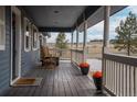 Inviting covered porch with rocking chairs and scenic views of the surrounding landscape at 30484 Chisholm Trl, Elizabeth, CO 80107