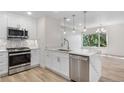 Bright white kitchen with stainless appliances, quartz countertops, and view of the breakfast area at 1308 Snowberry Ln # 302, Louisville, CO 80027