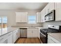 Modern kitchen features white cabinets, stainless steel appliances, and light countertops at 48229 Shetland Dr, Bennett, CO 80102