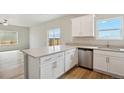 Eat-in kitchen with gray counters, white cabinets, stainless steel dishwasher, and hardwood-style floors at 48229 Shetland Dr, Bennett, CO 80102