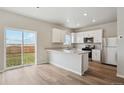 Bright, open kitchen featuring white cabinets, stainless steel appliances, and a sliding glass door to the backyard at 48229 Shetland Dr, Bennett, CO 80102