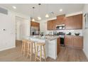 Kitchen area with stainless steel refrigerator, wood cabinets and granite counters and three barstools at 6153 N Ceylon St # 203, Denver, CO 80249