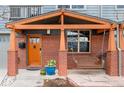 Inviting front porch with a cozy swing, brick pillars, and a vibrant flower arrangement at 84 Inca St, Denver, CO 80223