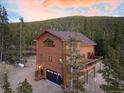 A view of the exterior shows a charming mountain home nestled in a forest with an inviting deck and mountain views at 57 Overlook Ct, Idaho Springs, CO 80452
