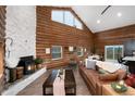 An inviting open-concept living space featuring a stone fireplace, wood walls, and large windows showcasing mountain views at 57 Overlook Ct, Idaho Springs, CO 80452