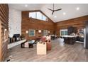 Spacious living room features wood walls, vaulted ceilings, a stone fireplace, and views of the surrounding forest at 57 Overlook Ct, Idaho Springs, CO 80452