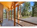 Inviting front porch featuring wooden beams, stone accents, and scenic views of the surrounding woods at 26196 Rea Ave, Conifer, CO 80433