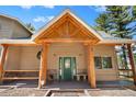 Covered porch with wooden beams, stone accents, and a cozy bench offers an inviting entry at 26196 Rea Ave, Conifer, CO 80433