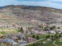 Scenic aerial view of homes and golf course nestled against rocky hills, offering a serene community setting at 16226 River Haven Way, Morrison, CO 80465