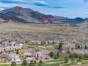 Picturesque aerial view showcasing homes alongside a golf course, set against a backdrop of rolling hills and red rock formations at 16226 River Haven Way, Morrison, CO 80465