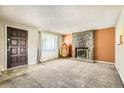 Living room featuring rock fireplace, vintage juke box, carpeted floor, and front door at 7542 Otis St, Arvada, CO 80003