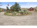 Rural property featuring a house, red barn, and a unique decorative island in the circular driveway at 12101 Riverdale Rd, Brighton, CO 80602