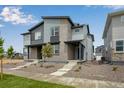 Modern townhome showcasing its gray facade, brick accents, and professionally landscaped front yard at 1418 Hudson Pl, Longmont, CO 80501