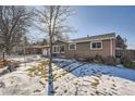 Brick ranch house with a snow-covered lawn and mature trees at 6995 S Ash Cir, Centennial, CO 80122