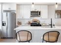 Bright kitchen features white subway tile backsplash, stainless steel appliances, quartz countertops, and counter seating at 2920 W Parkside Pl, Denver, CO 80221