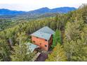 Aerial view of a wood home with a green roof surrounded by a dense forest landscape at 11876 Coal Creek Heights Dr, Golden, CO 80403