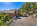 Exterior view of a home with a detached garage and gravel driveway at 11876 Coal Creek Heights Dr, Golden, CO 80403