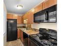 Functional kitchen featuring wood cabinets, black appliances, granite countertops, and tiled backsplash at 5995 E Iliff Ave # 317, Denver, CO 80222