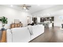 Spacious living area featuring hardwood floors, a white sofa, and a glimpse into the modern kitchen at 8814 S Winnipeg Ct, Aurora, CO 80016