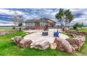 Backyard patio area has stone accents, a fire pit and chairs for relaxing, surrounded by lush green grass at 1820 S State 83 Hwy, Franktown, CO 80116