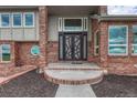 Home's entryway with a modern design front door, brick exterior, and a round window to the side at 1820 S State 83 Hwy, Franktown, CO 80116