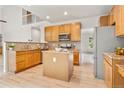 Well-equipped kitchen featuring wood cabinets, granite countertops, a kitchen island, and stainless steel appliances at 6310 W Sumac Ave, Littleton, CO 80123