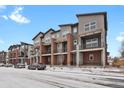 Modern townhome exteriors featuring brick accents, private balconies, and snowy street view on a partly cloudy day at 7870 W 43Rd Pl, Wheat Ridge, CO 80033
