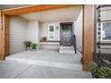 Inviting front porch with neutral-toned exterior, dark door, wooden beam supports, and potted plants at 18438 E Berry Dr, Centennial, CO 80015