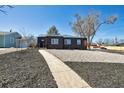 Inviting home exterior with dark siding, gravel landscaping, and a quaint walkway at 1285 Roslyn St, Denver, CO 80220