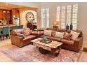 Bright living room featuring large windows, leather sofas, an unique coffee table and an open connection to the kitchen at 9238 Viaggio Way, Highlands Ranch, CO 80126