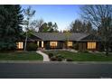 Dusk view of brick single-story with inviting glowing windows and mature trees at 5290 Nassau E Cir, Cherry Hills Village, CO 80113