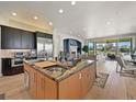 Open-concept kitchen with a large island, stainless appliances, and adjacent living area at 1287 Buffalo Ridge Rd, Castle Pines, CO 80108