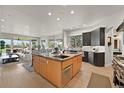 A spacious kitchen with stainless steel appliances and stone countertops overlooks the home's living and dining spaces at 1287 Buffalo Ridge Rd, Castle Pines, CO 80108