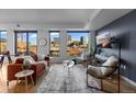 Sunlit living room boasts hardwood floors, floor-to-ceiling windows with city skyline views, and stylish modern decor at 1750 Wewatta St # 830, Denver, CO 80202