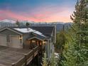 Exterior view of a mountain home featuring a large deck with snow-capped mountains in the background at sunset at 85 Uncle Sam Lode, Breckenridge, CO 80424