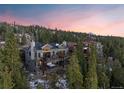 Multi-level home nestled in a forest with balconies, and a hot tub, all against a backdrop of a colorful sunset sky at 85 Uncle Sam Lode, Breckenridge, CO 80424