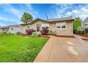 Inviting home featuring a stone facade, tidy landscaping, and a concrete driveway leading to the entrance at 3450 W Amherst Ave, Denver, CO 80236