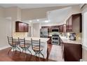 Modern kitchen features stainless appliances, dark wood cabinets, and a breakfast bar with seating for four at 3450 W Amherst Ave, Denver, CO 80236